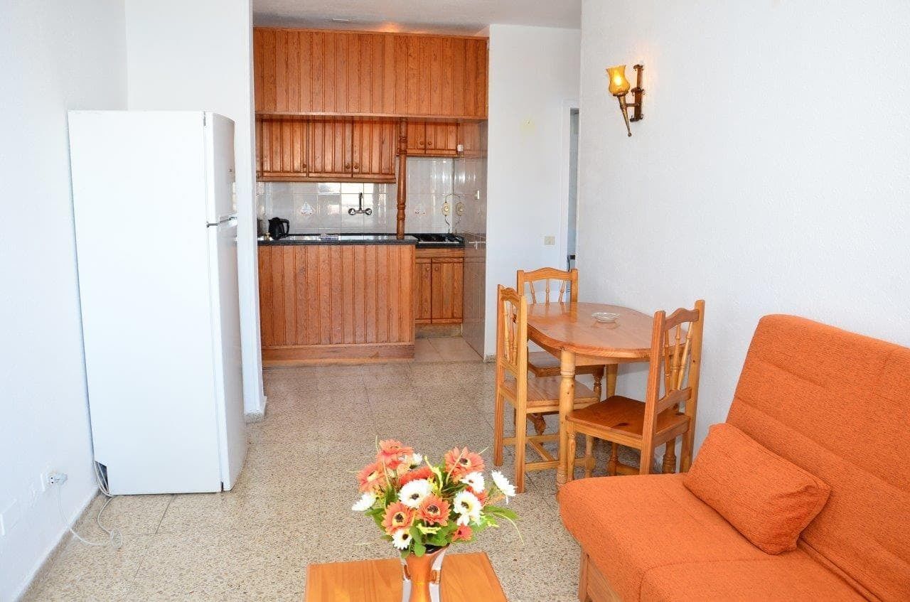A compact living space with a kitchenette, a dining area with wooden furniture, and a sofa.
