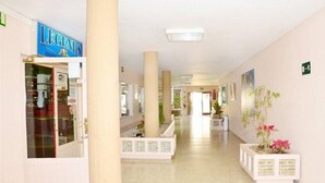 A hotel corridor with a 'LEGENDS' sign, white pillars, and potted plants. - Apartamentos Costamar (Arona)