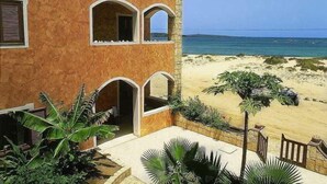 Ein Gebäude mit Blick auf den Strand, mit einer Steinfassade und Bogenfenstern.