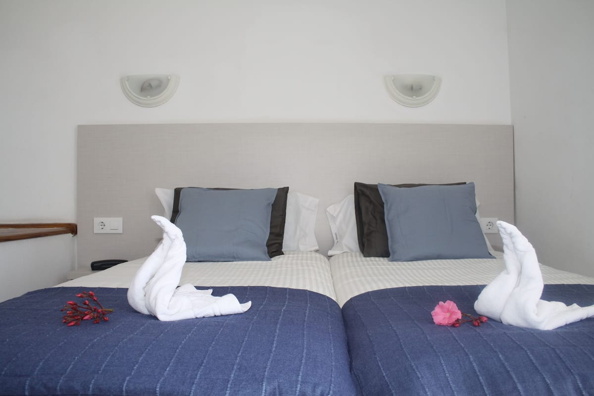 A double bed with two pillows, a headboard, and a wall socket.