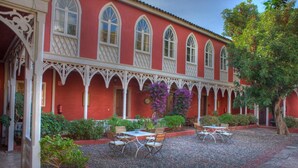 Ein rotes Gebäude mit weißen Bögen und einem Innenhof mit Tischen und Stühlen.