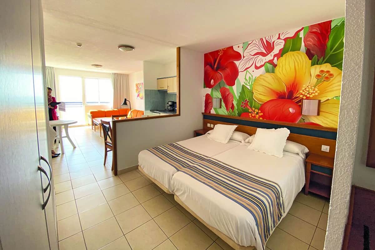 A hotel room with a large bed, a dining area, and a kitchen.