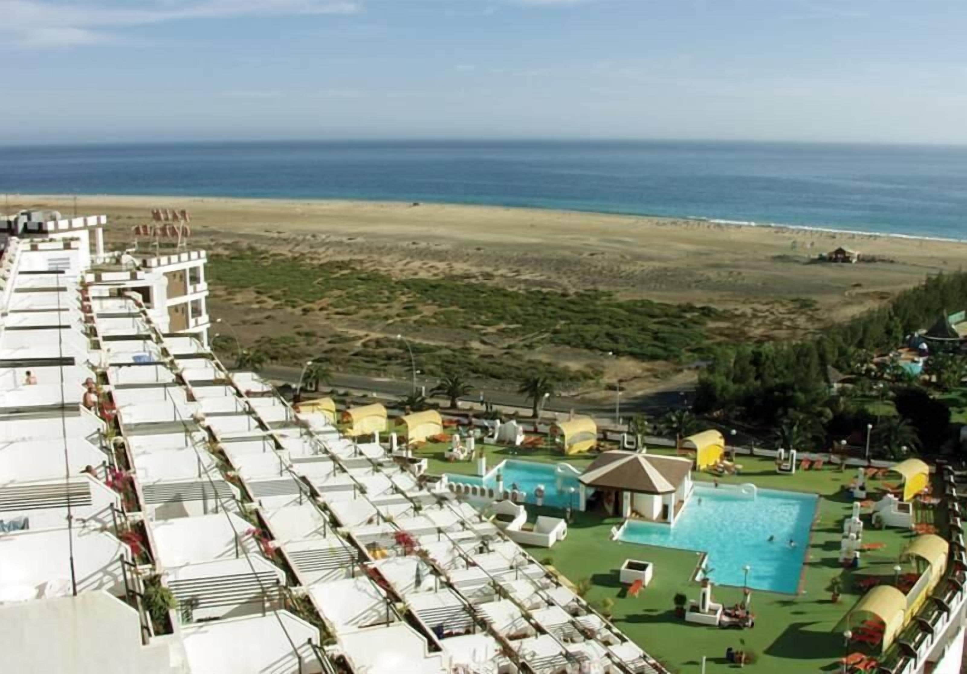A cruise ship deck with rows of sun loungers and a swimming pool.