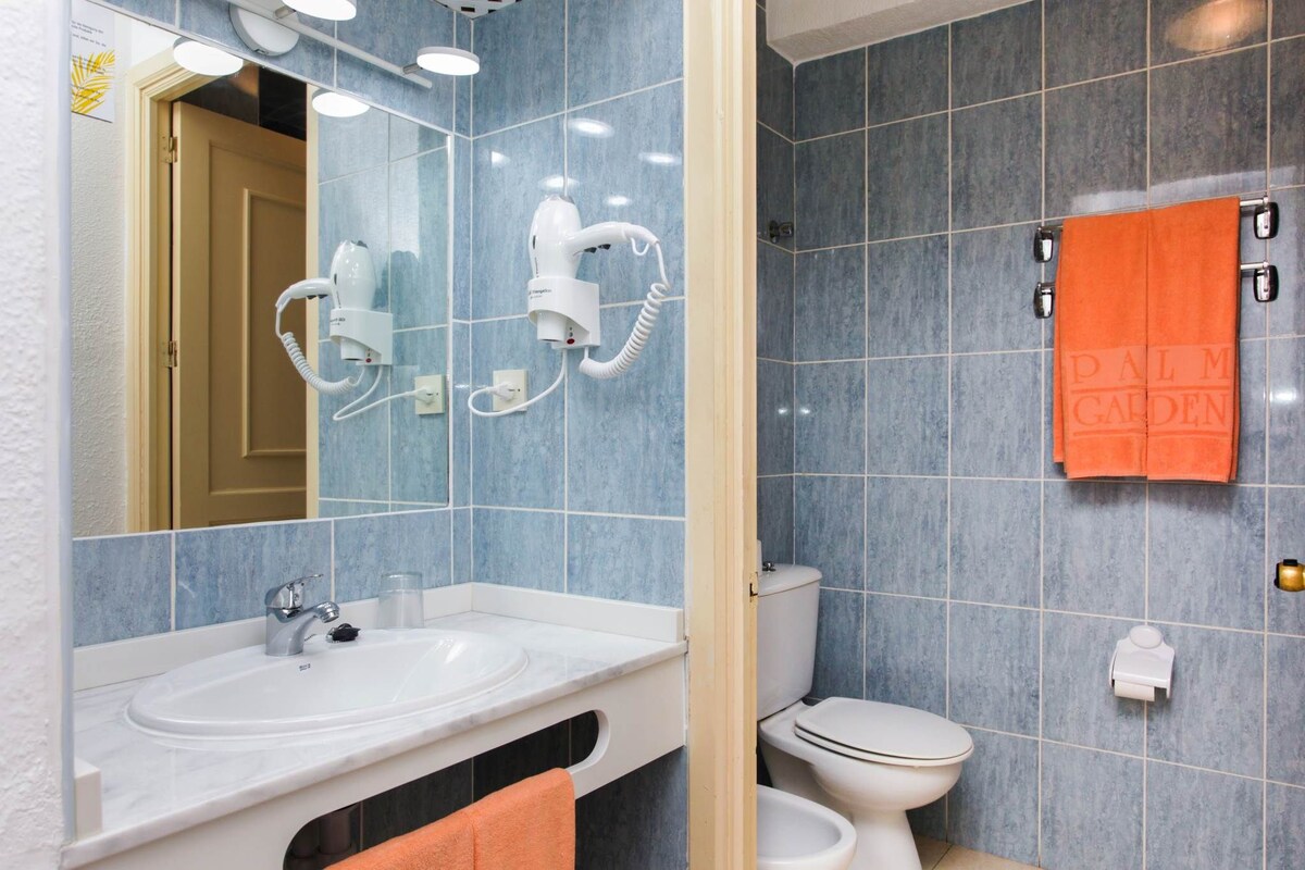 A bathroom with a sink, mirror, hairdryer, and towel rack.