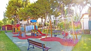 Une aire de jeux avec un toboggan, des balançoires et un banc.