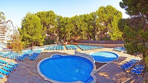 Un espace piscine comprenant plusieurs piscines et des chaises longues.