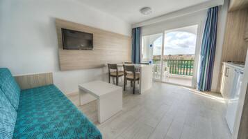 A modern hotel room with a bed, a small desk, a TV mounted on the wall, and a balcony with curtains.
