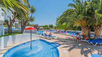 Una piscina al aire libre, sombrillas, sillones reclinables de piscina