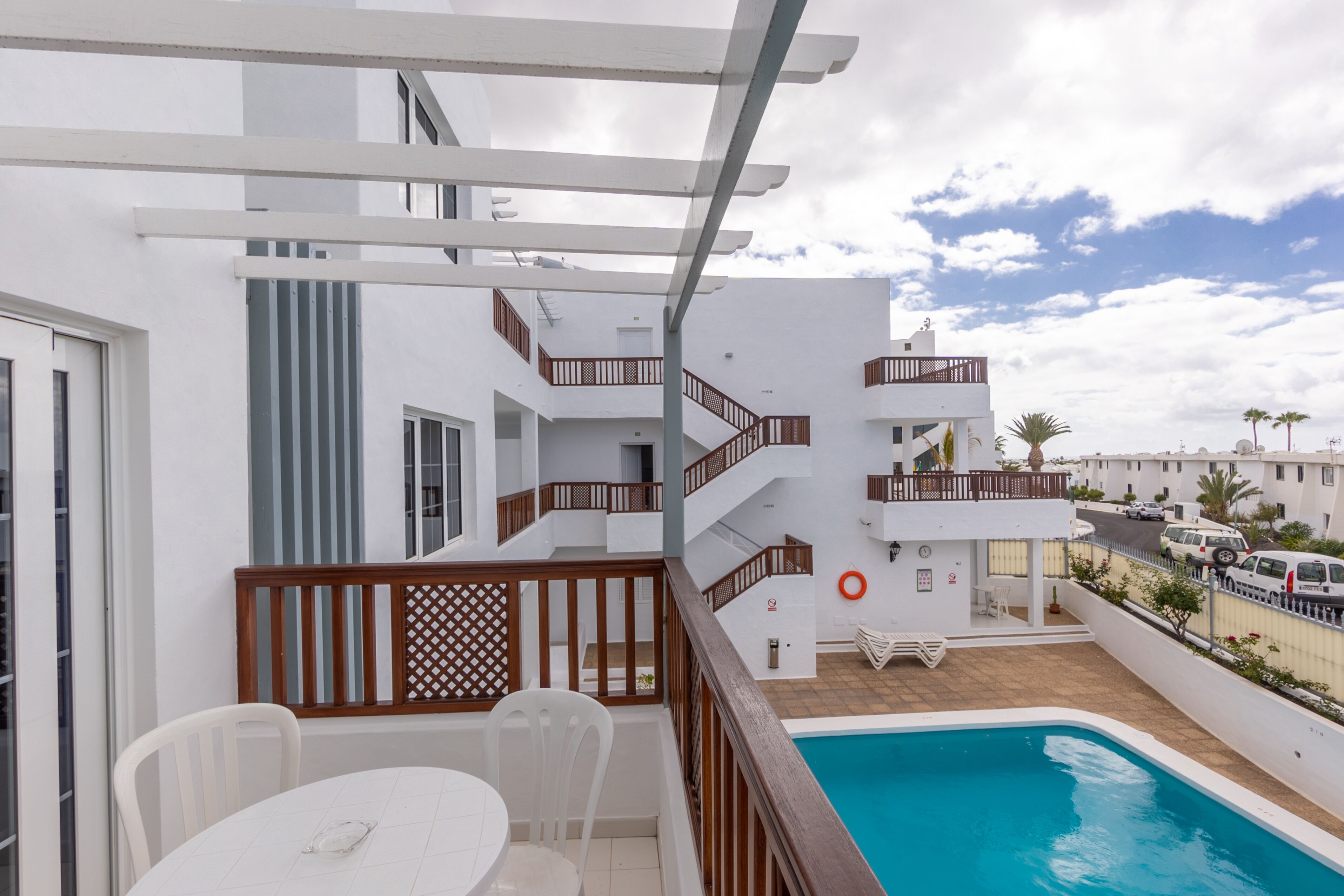 A modern building with a pool, white walls, and balconies.