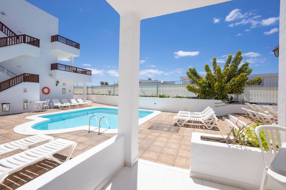 A rooftop pool area with sun loungers and a clear blue sky.