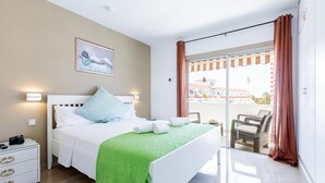 A bedroom with a bed, a nightstand, a chair, and a view of the outside. - Las Floritas (Arona)