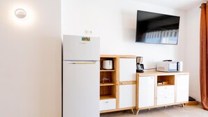 A compact kitchen with a refrigerator, microwave, and wooden cabinets. - Las Floritas (Arona)