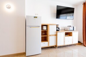 Une cuisine de taille réduite, équipée d’un réfrigérateur, d’un four à micro-ondes et de meubles de rangement en bois.