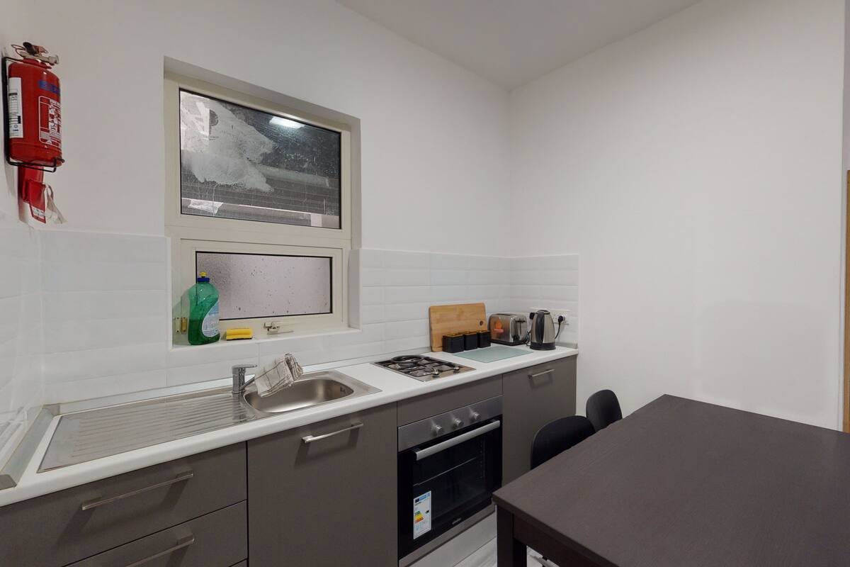 A compact kitchen with a gas stove, sink, and a window above the countertop.