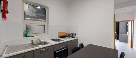 A compact kitchen with a gas stove, sink, and a window above the countertop.