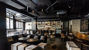A modern bar with a variety of seating options, including sofas and tables, and a well-stocked bar area with shelves of bottles.