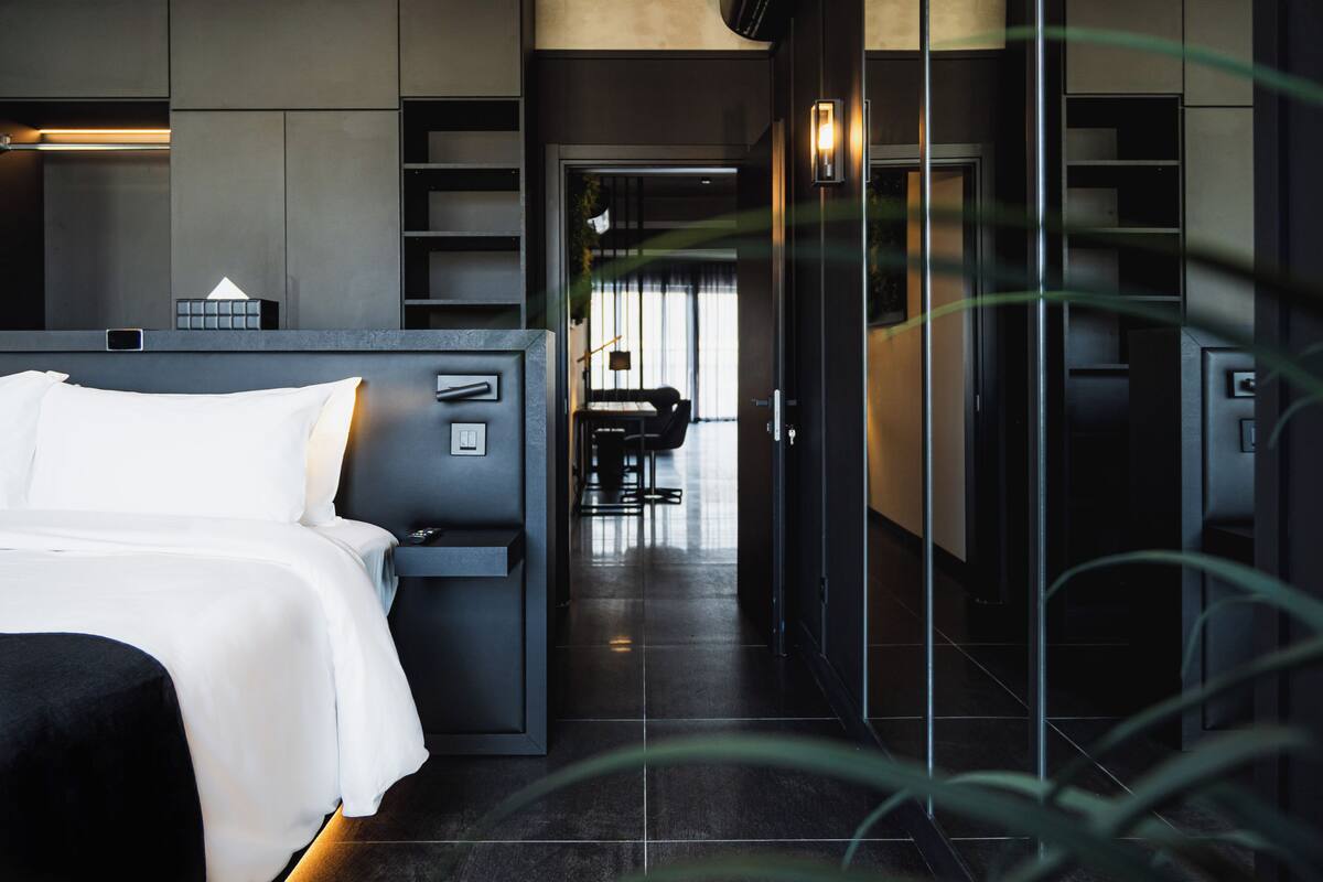 A modern hotel room with a bed, a desk, and a walk-in closet.