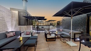 An outdoor seating area with sofas, tables, and umbrellas.