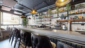 A bar area with a long counter, multiple stools, and a variety of liquor bottles on shelves.