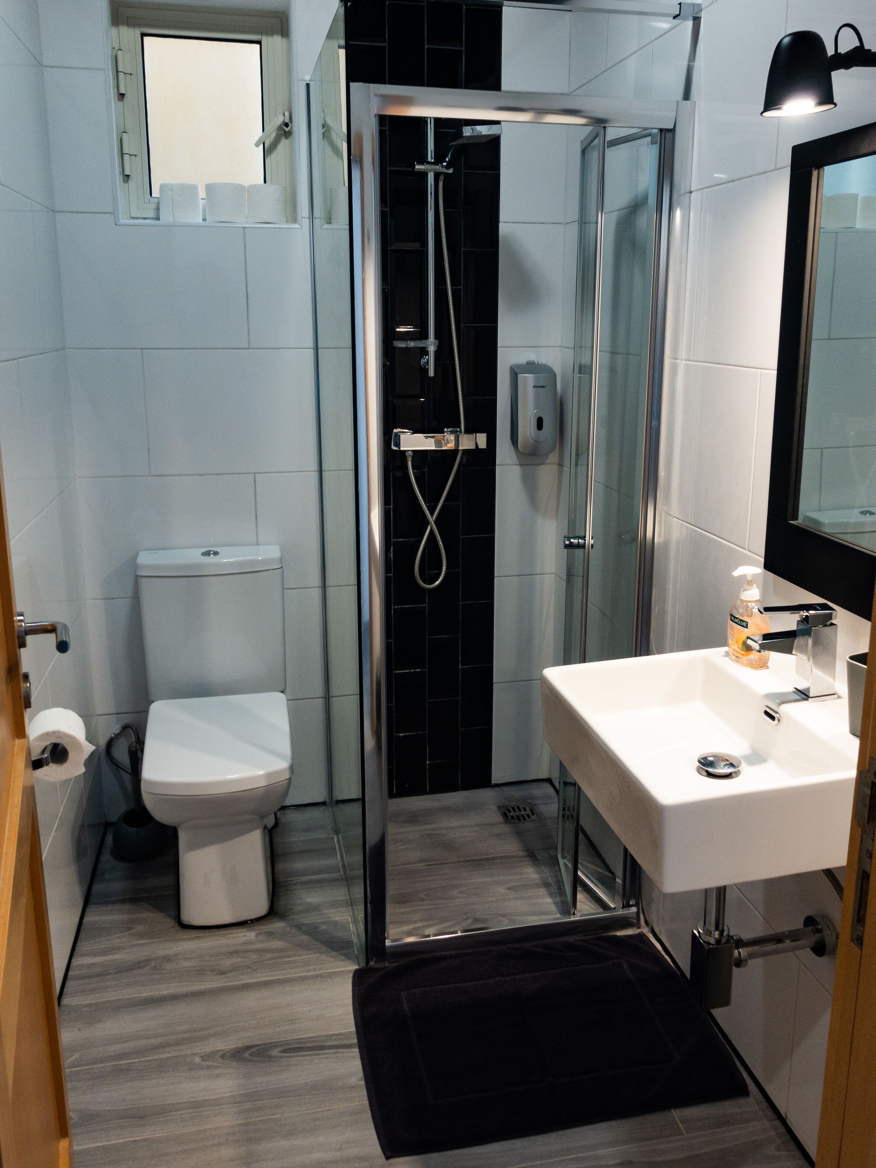 A modern bathroom with a toilet, shower, and sink.