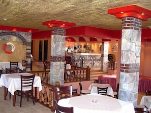 A restaurant with stone pillars, tables with white tablecloths, and a bar area. - Amaris (Sunny Beach)