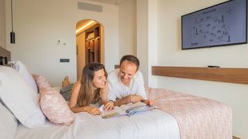 Una pareja leyendo un libro en una cama, con un mapa de Menorca en la pared.