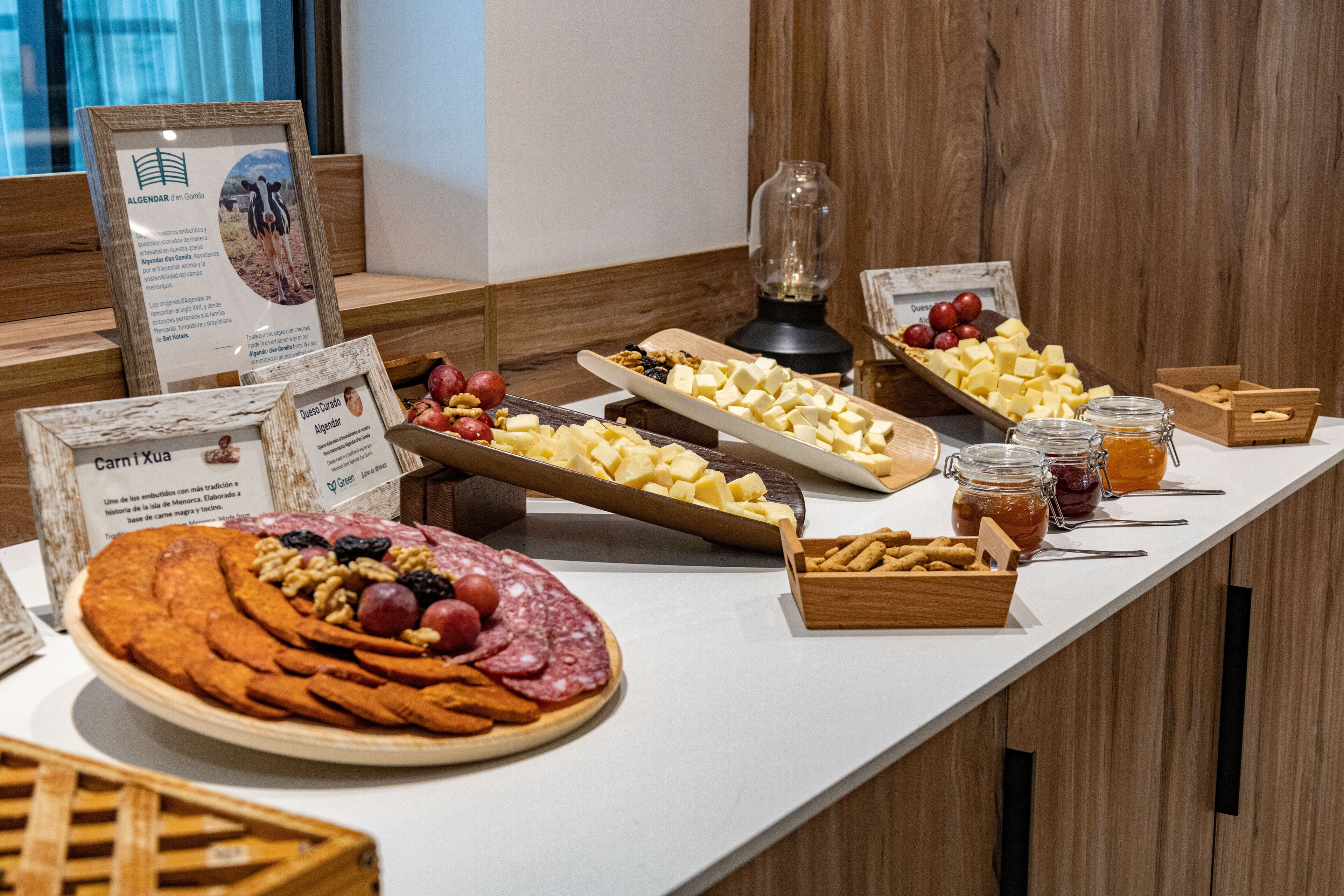 Una mesa de buffet con diversos alimentos, entre ellos queso, frutas y frutos secos.
