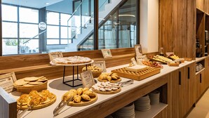 A buffet with various pastries and desserts displayed on a wooden counter.