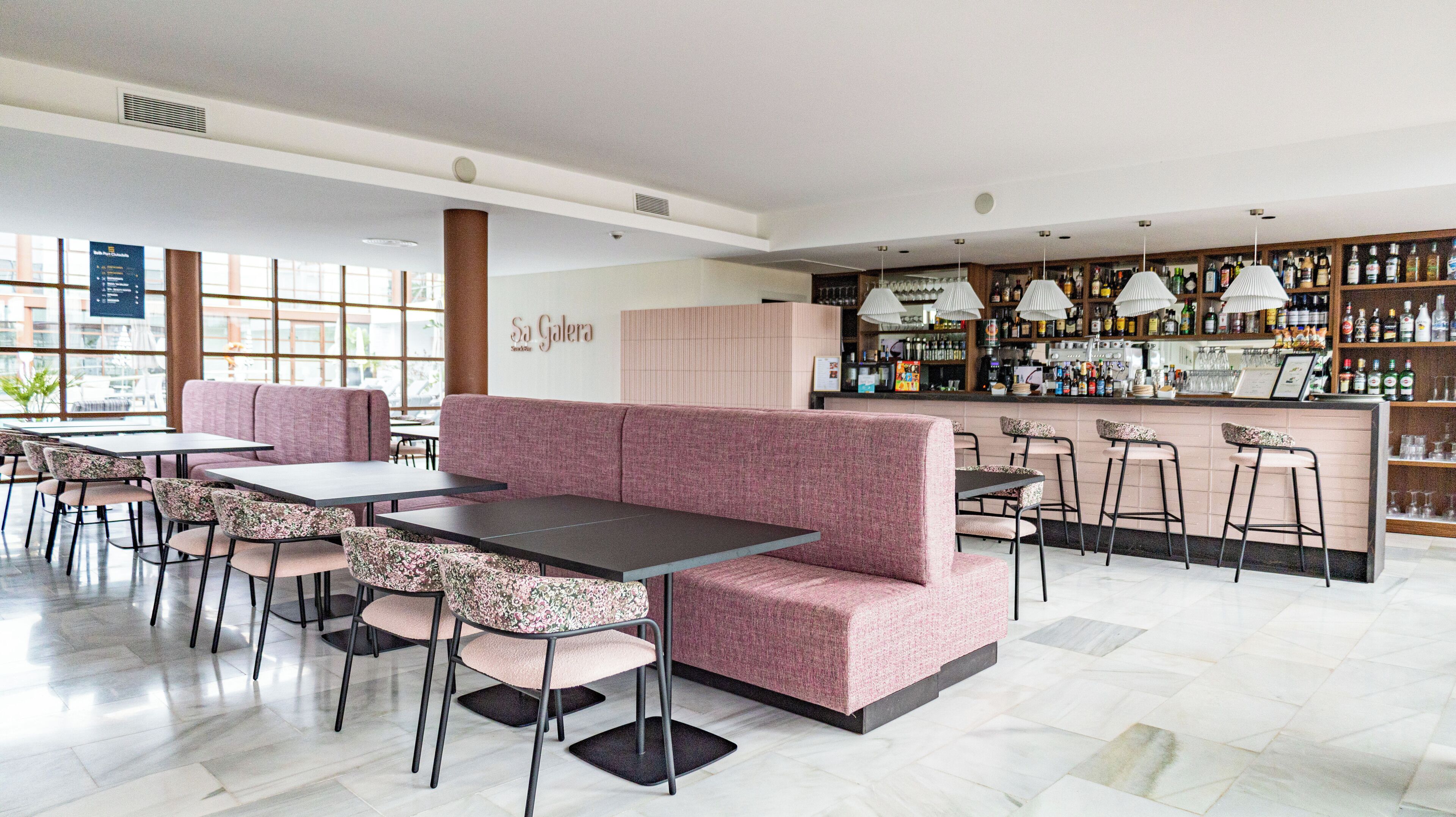 A restaurant with pink seating, a bar area with bottles, and a sign reading "Sa Galera".