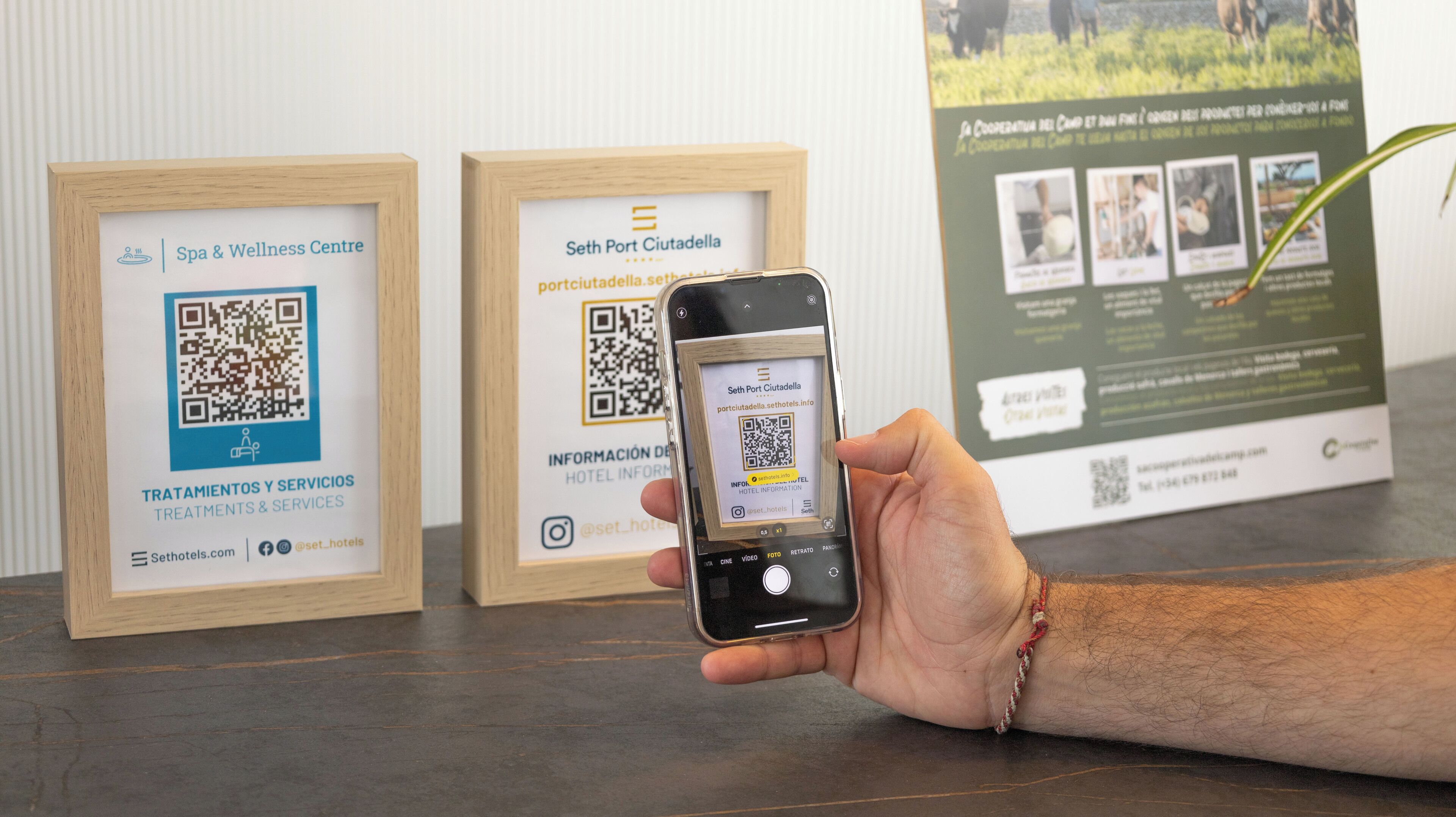 A hand holding a smartphone displaying a QR code for Seth Port Ciudadella.