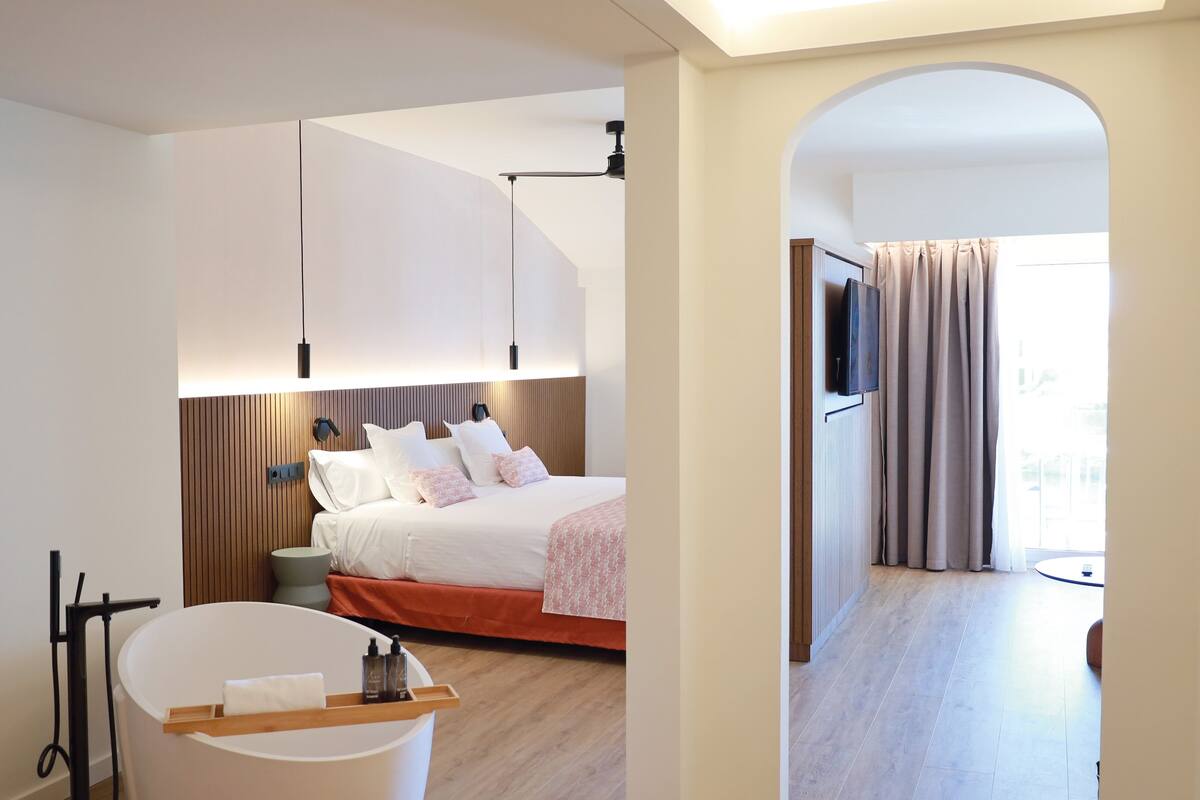 Ein modernes Hotelzimmer mit Bett, Nachttisch und einem an der Wand befestigten Fernseher.