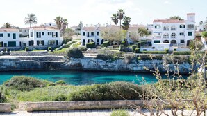 A coastal town with white buildings, a clear blue sea, and a rocky shoreline.