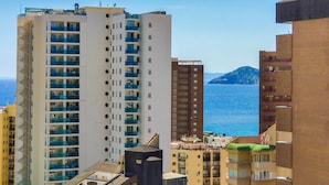 Ein Hochhaus mit mehreren Balkonen, Blick auf das Meer und eine entfernte Insel.