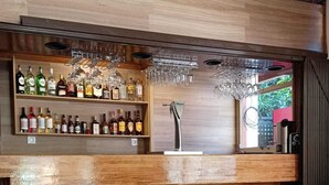 Eine Bar mit Regalen voller Spirituosenflaschen, einem Zapfhahn und hängenden Gläsern.