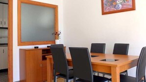 Ein Essbereich mit Holztisch und schwarzen Stühlen, einem Holzschrank und einem Gemälde an der Wand.