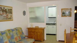 Ein kleiner, gemütlicher Wohnraum mit einer Couch, einem Holzschrank und einem Esstisch.