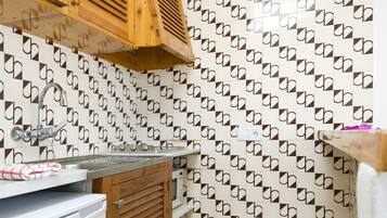Una cocina compacta con un lavamanos, armarios de madera y un salpicadero decorativo.