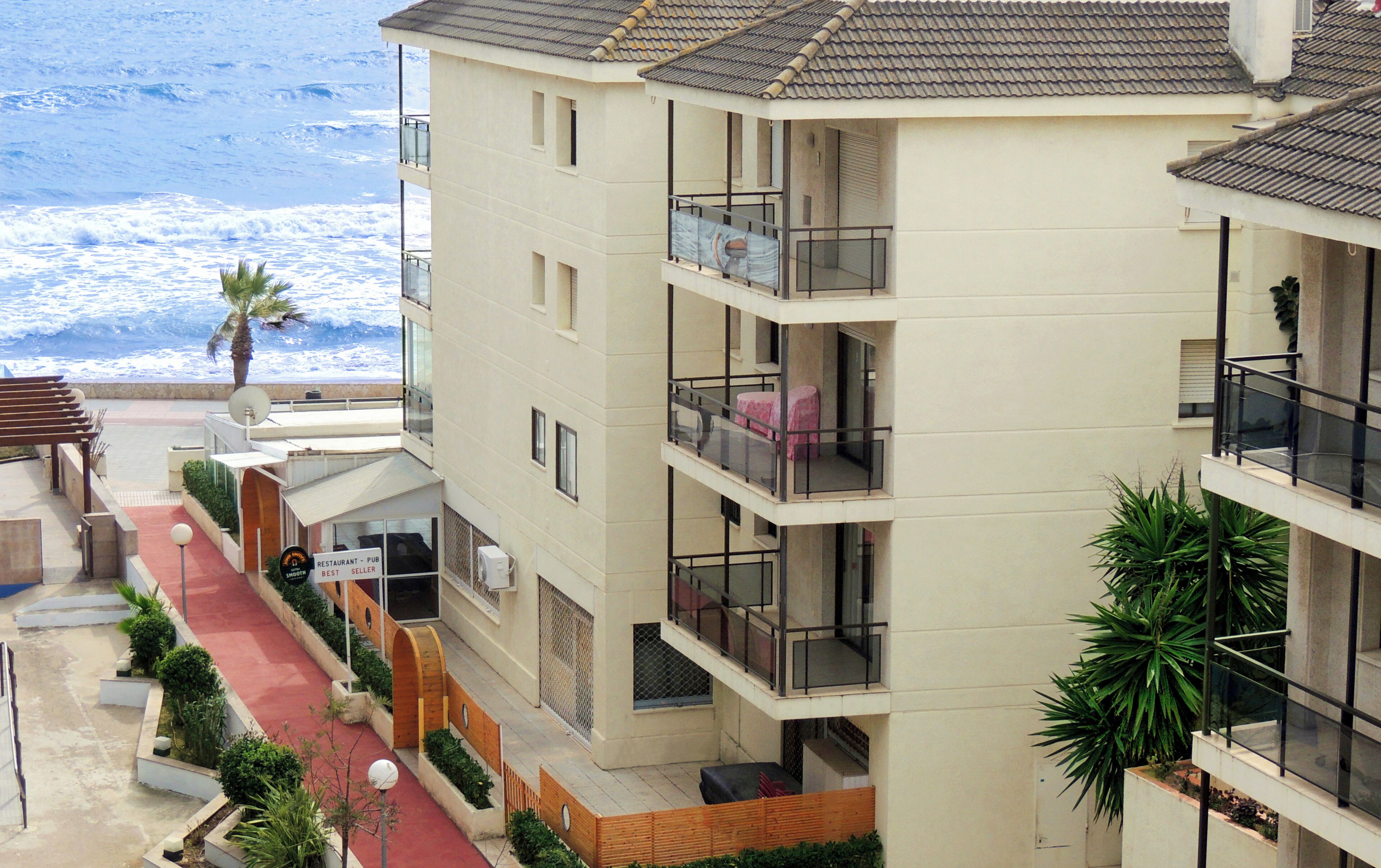 Un hotel de varios pisos con balcones, un pasillo alfombrado de rojo y vistas al mar.