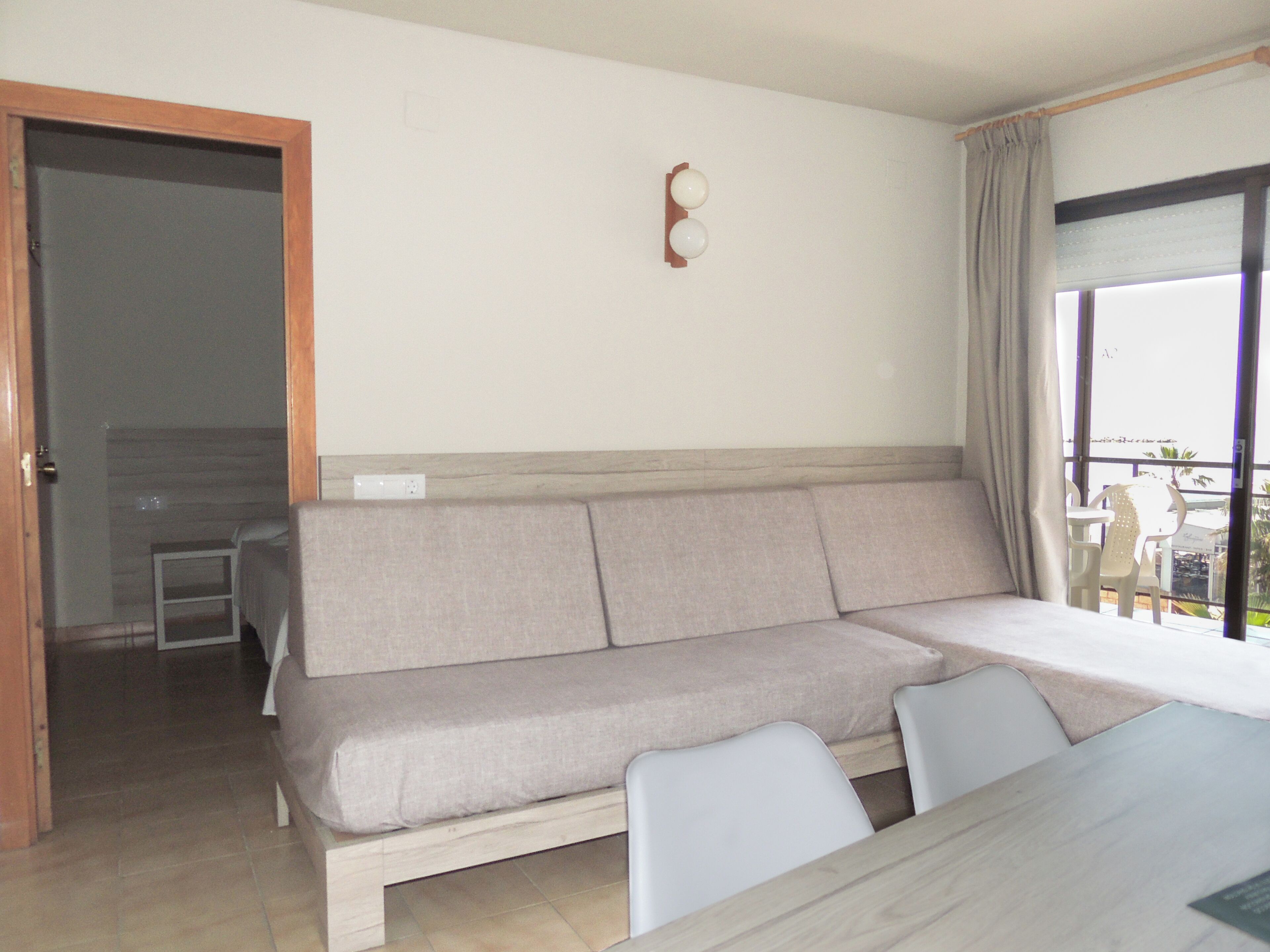 A modern room with a sofa, a dining table, and a view through a window.