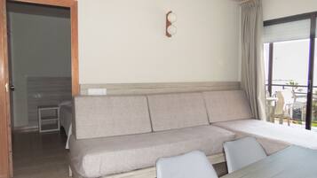A modern room with a sofa, a dining table, and a view through a window.