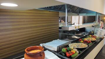 A buffet with various food items and a large pot of soup.