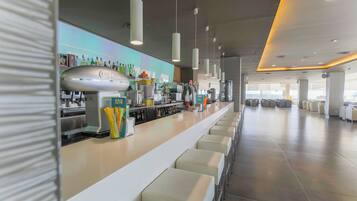 Zona de bar moderna amb una barra llarga, diverses opcions de seients i una varietat d'equipatge de bar.
