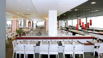A modern restaurant with multiple dining areas, including a buffet and a bar.