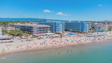 Un complex turístic a la platja amb diversos edificis hotelers, sorra daurada i aigües blaves cristal·lines.