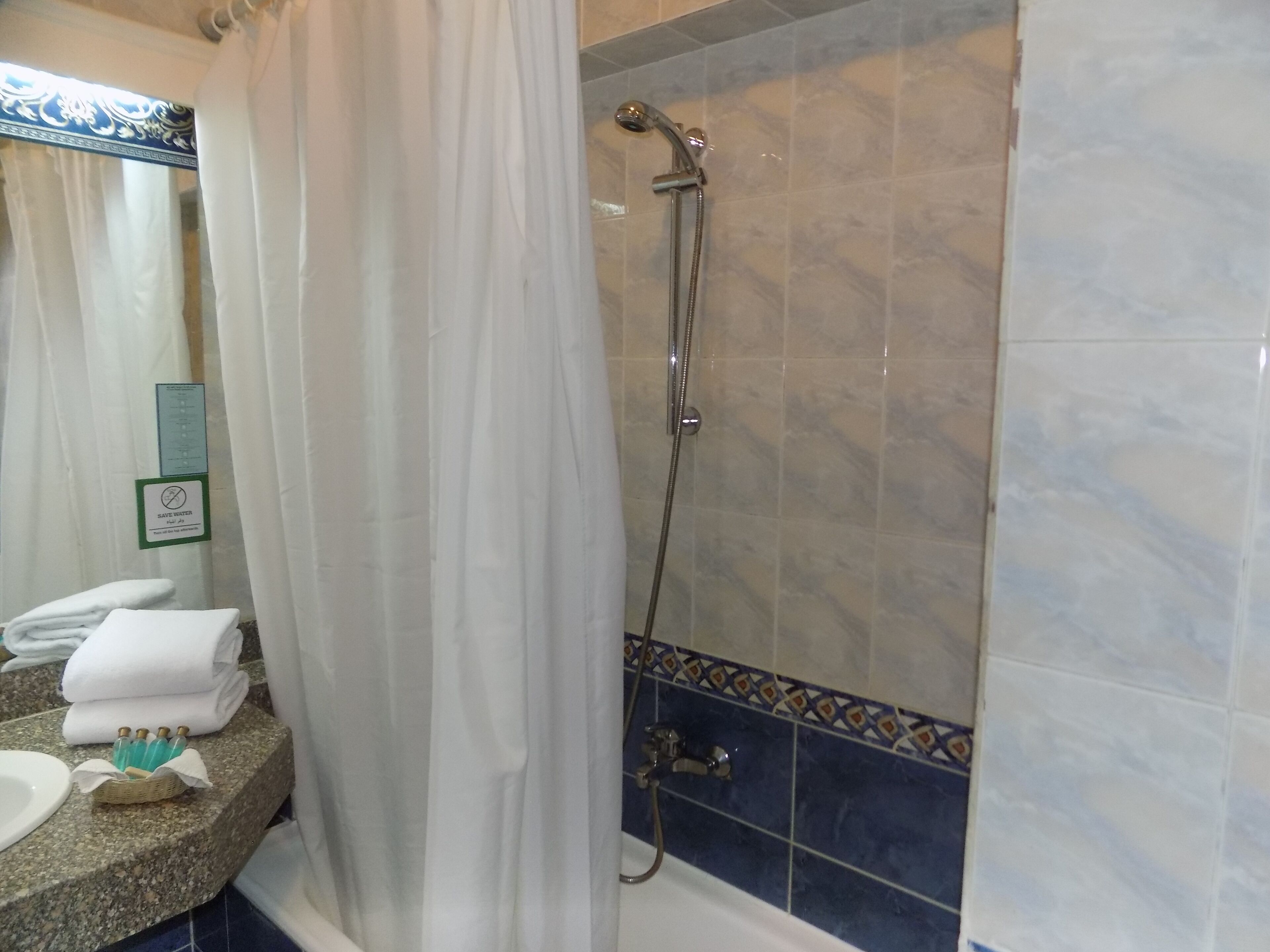 Un baño con ducha, lavabo y toallero.