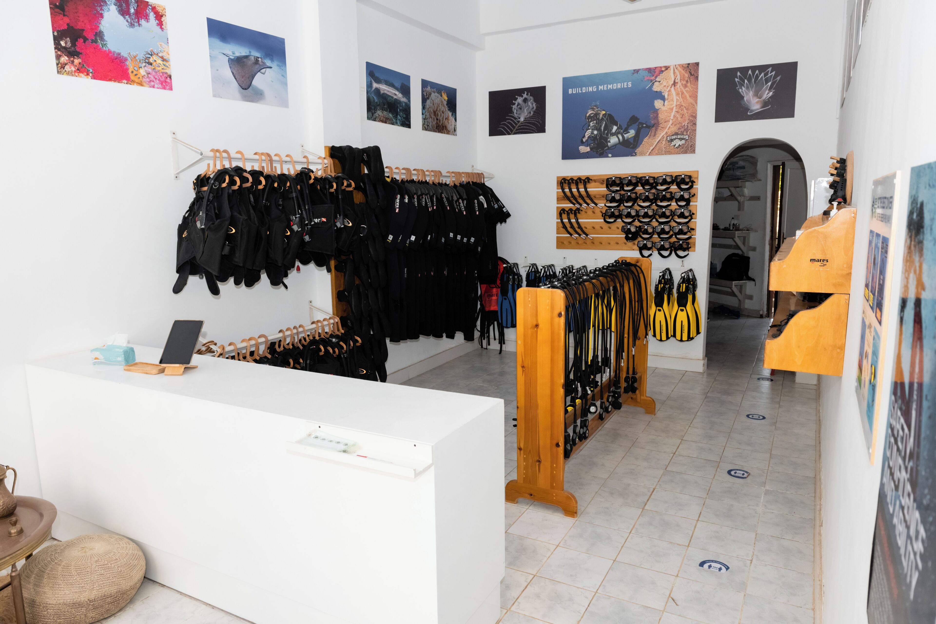 A retail store with racks of black clothing and accessories, a reception desk, and various posters on the walls.