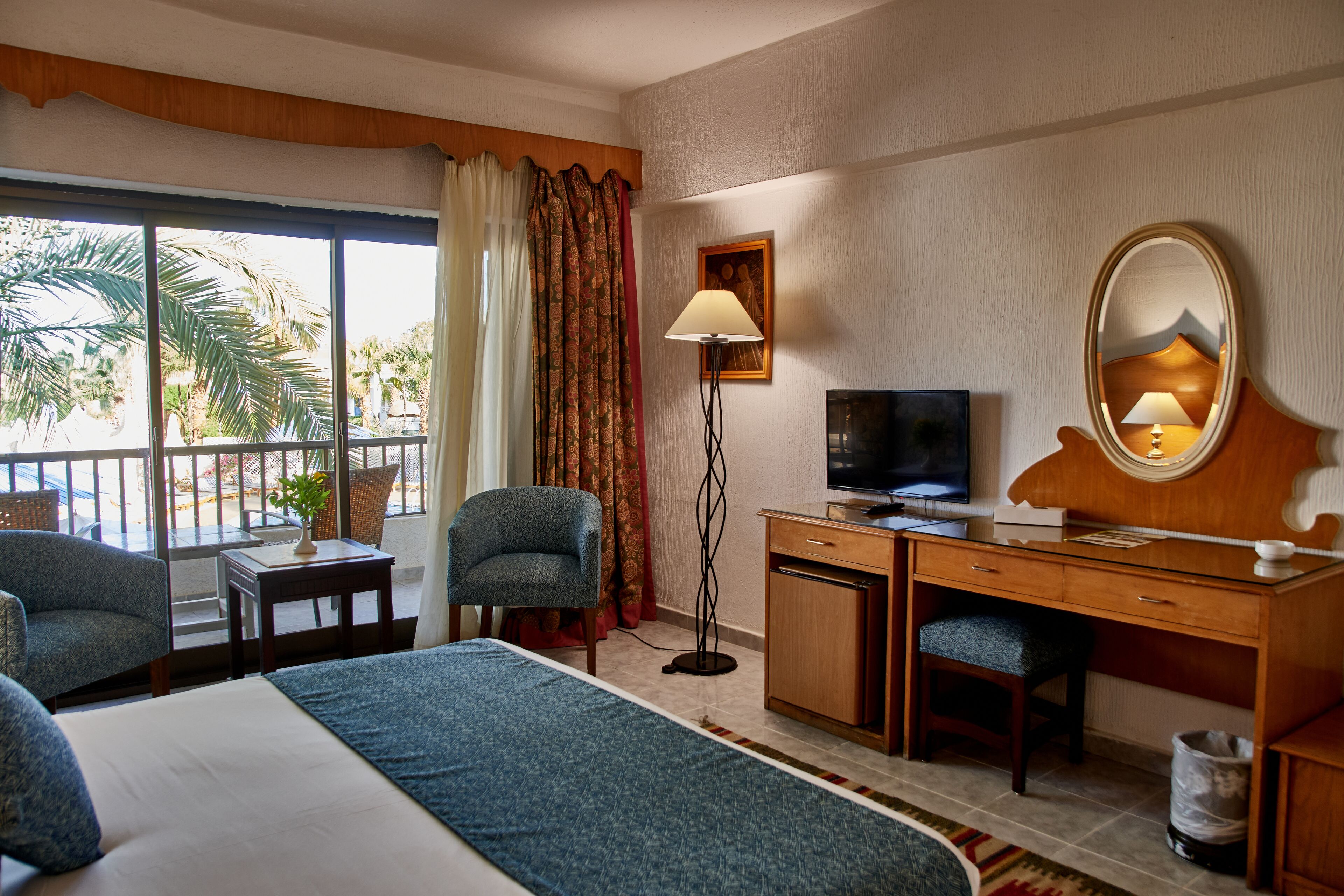 Een hotelkamer met een groot bed, een bureau met een computer, een stoel, een televisie en een raam met gordijnen.