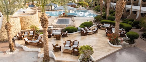 A resort pool area with lounge chairs and palm trees.