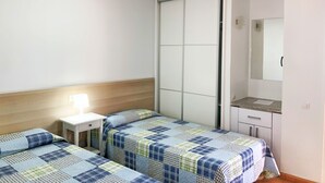 Un dormitorio con dos camas, una mesita de noche, un aparador y un espejo.