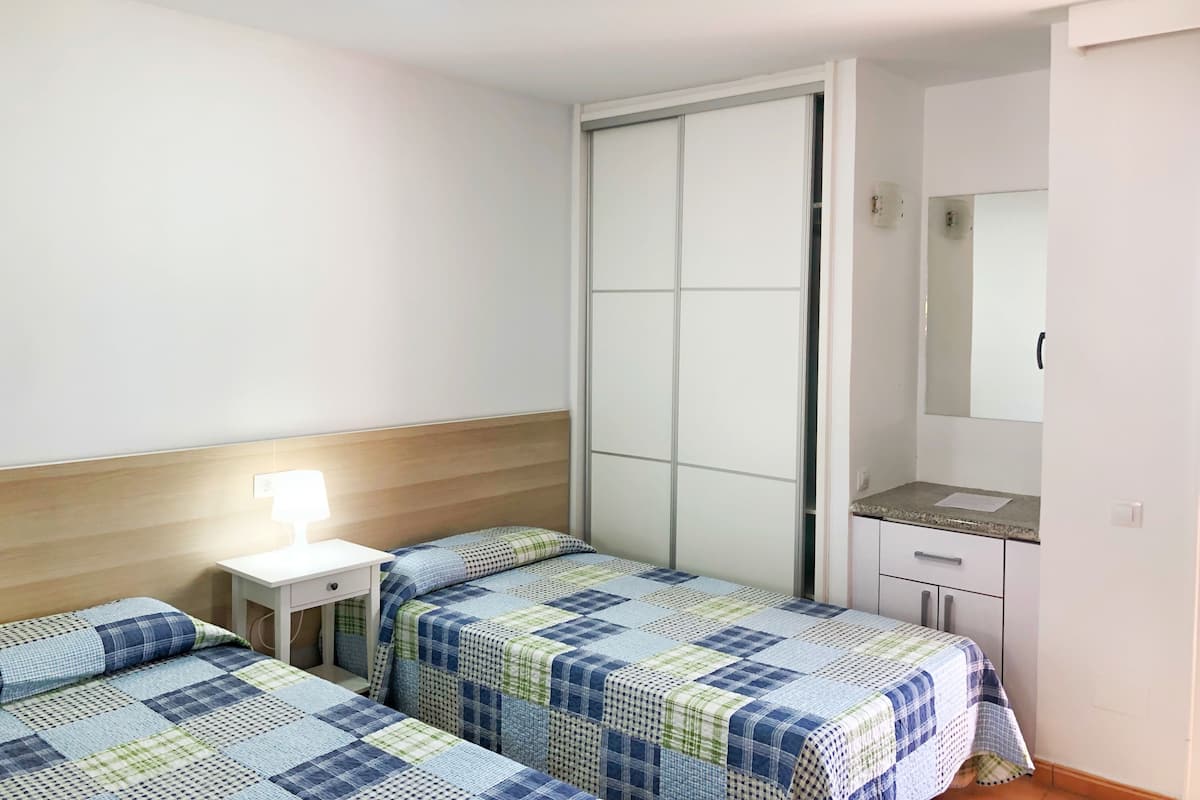 Un dormitorio con dos camas, una mesita de noche, un aparador y un espejo.